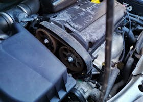 Detailed close-up of a car engine focusing on the belts and components under the hood.