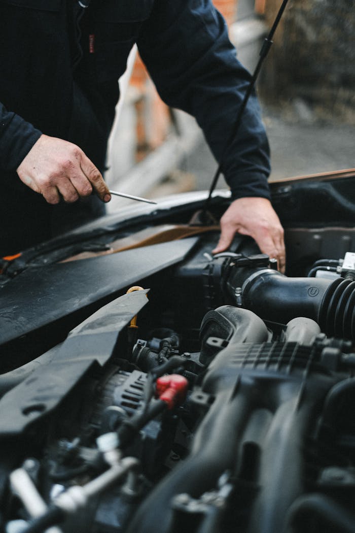 A mechanic working on a car engine with tools, focused on repairs.